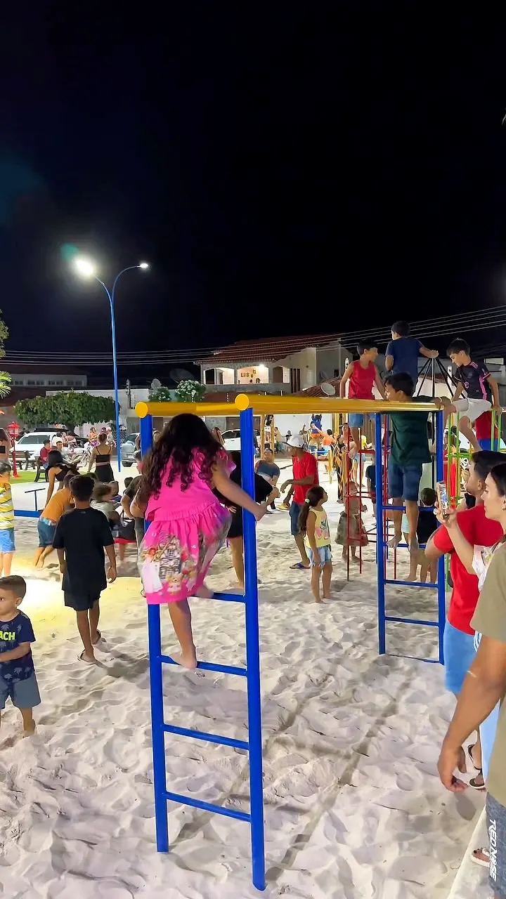 Crianças brincando em playground à noite numa praça
